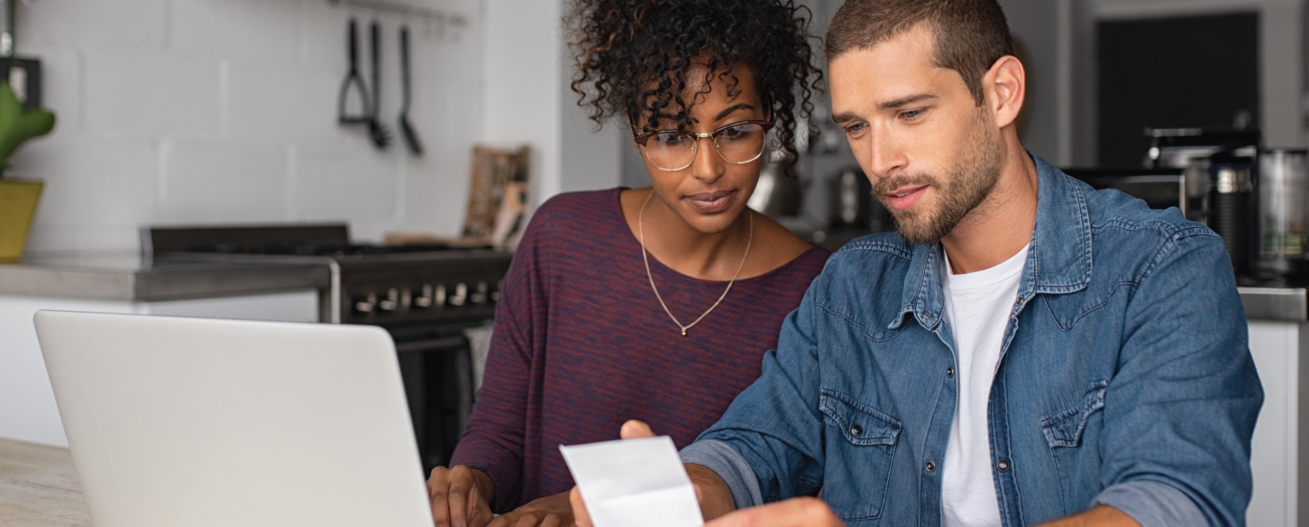 A couple reviews a receipt and uses their laptop to check for signs of identity theft.